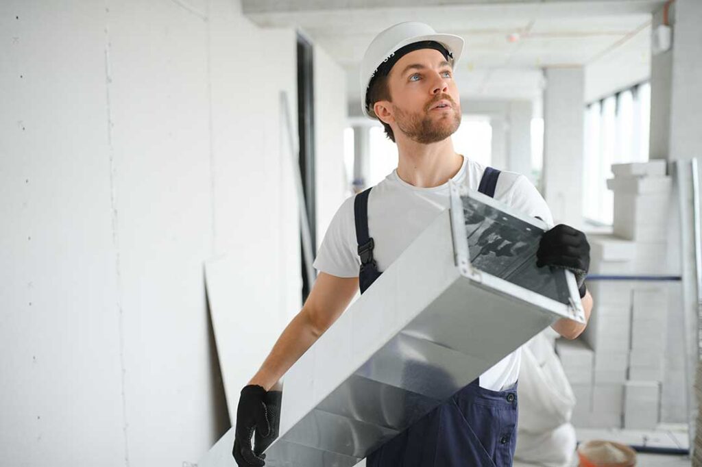 A person replacing a dirty HVAC filter in a residential furnace closet