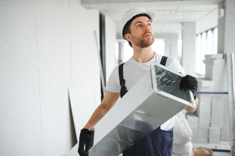A person replacing a dirty HVAC filter in a residential furnace closet
