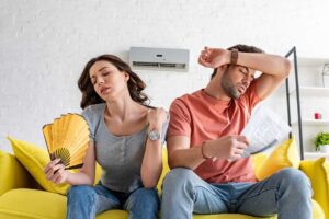 A family changes the air filter on a central home HVAC system inside a living room.