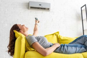 A hand adjusting a digital thermostat on a neutral-colored wall inside a residential home.